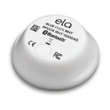 ela Blue PUCK RHT, runder weisser Bluetooth-Sensor für Temperatur und Luftfeuchtigkeit in Schrägansicht mit Typenschild auf der Oberseite